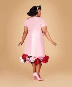 Susie wearing a pink satin American Beauty Dress with short sleeves and a bounty of embellished silk roses at the hem.